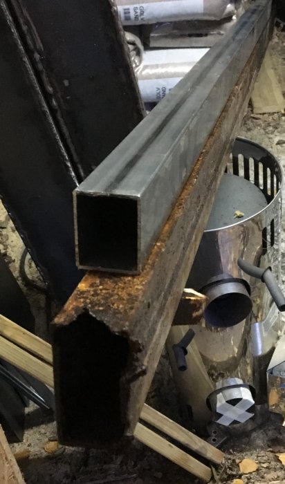 Stålrör som jämförs, nytt rör överst och rostigt rör under i en verkstadsmiljö.