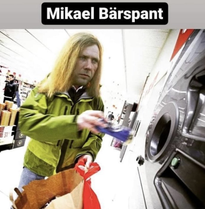 Person i grön jacka pantar flaskor vid en pantautomat.