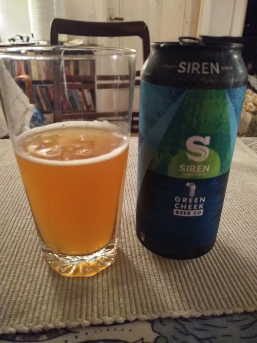 Ölglas delvis fyllt med orangefärgad öl bredvid en ölburk från Siren Craft Brew.