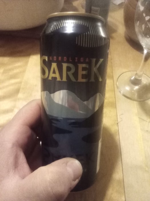 En hand håller en burk med texten "SAREK" och design som påminner om berg eller vågor.