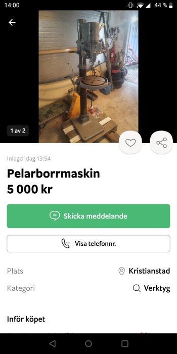 Pelarborrmaskin i ett garage miljö med diverse verktyg och utrustning i bakgrunden.