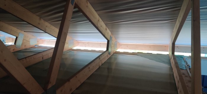 Vind med träbjälkar och nätting för ventilation inför isolering.