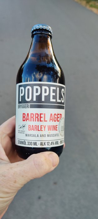 Hand håller en flaska Poppels Barrel Aged Barley Wine öl.