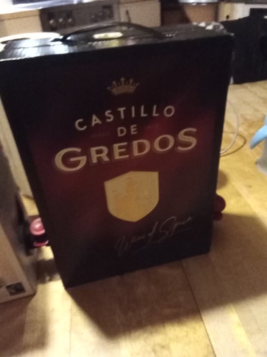 En box vin märkt Castillo de Gredos placerad på ett golv i ett kök.