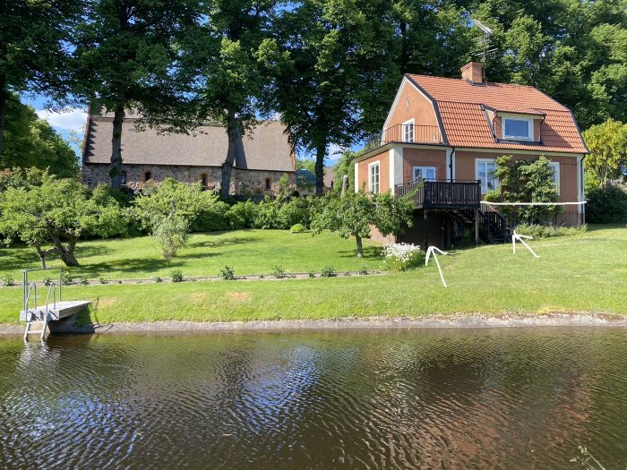 Hus från 1923 med befintlig altan bak och vit markering för ny altanplats, vid vatten med brygga.