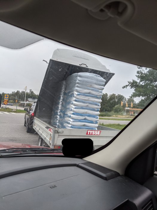 Bild sedd från bilens förarsida visar en släpvagn med högt lastade säckar som inte är fastsurrade.