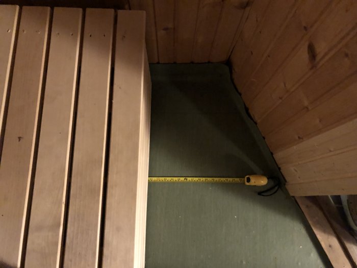 Bild på en bastus hörna med ett måttband som visar bredden på 140 cm vid lavarna.