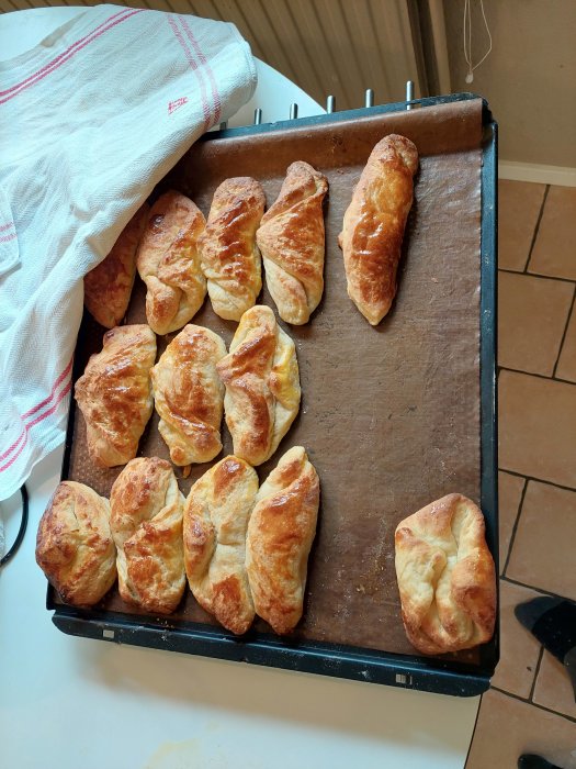 Hembakta croissanter och surdegsbullar på en bakplåt, varierande form och gräddning.