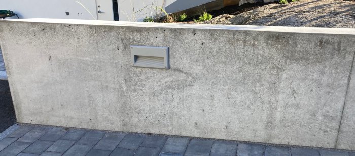 Del av en betongmur med minimala blåsor och en ventilationsspringa, storlek ungefär 2,2x0,7 meter.