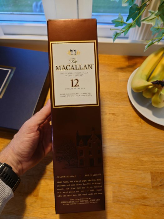 Flaska av The Macallan 12-årig single malt scotch whisky hållen av en person.