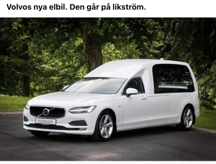 Vit modifierad elbil med likbilsdesign parkerad utomhus.