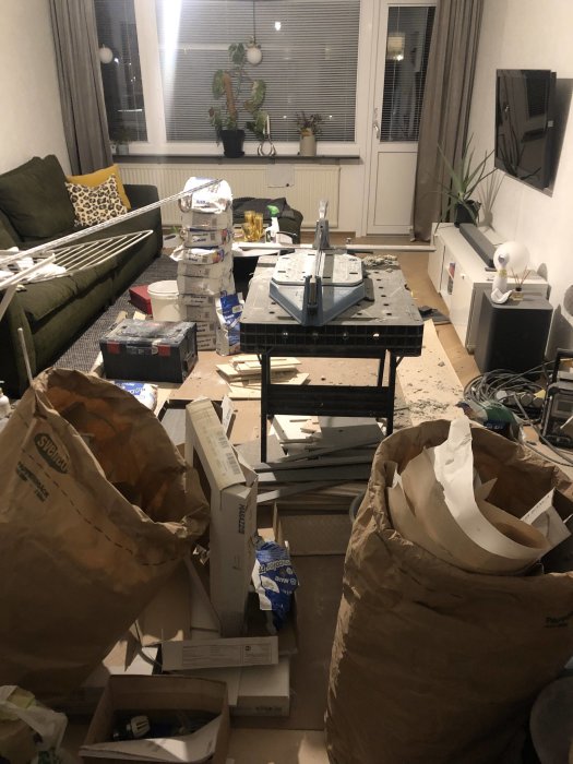 Vardagsrum fyllt med byggmaterial och damm under renovering.