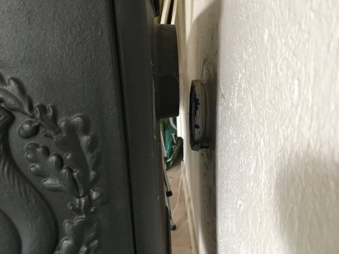 Kakelugn intill vit vägg med synlig nivåskillnad där rökröret ska anslutas, ca 8 cm höjdskillnad.
