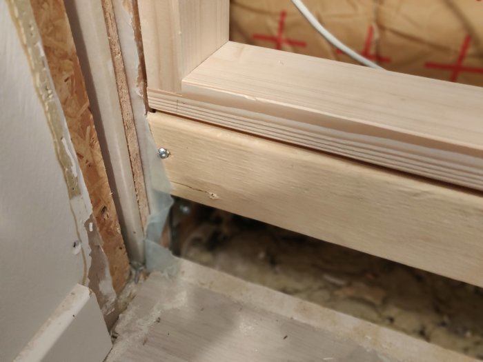 Delvis installerad dörrfoder med synlig ångspärr och isolering i en oavslutad konstruktion.