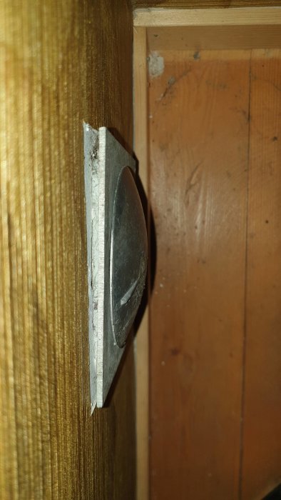 Gammal tallriksventil i trävägg, stängd men med synligt utrymme som släpper in kall luft.
