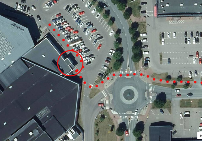 Flygbild över korsning med markerad cykelväg som leder in i parkeringsområde istället för tidigare asfalterad yta.