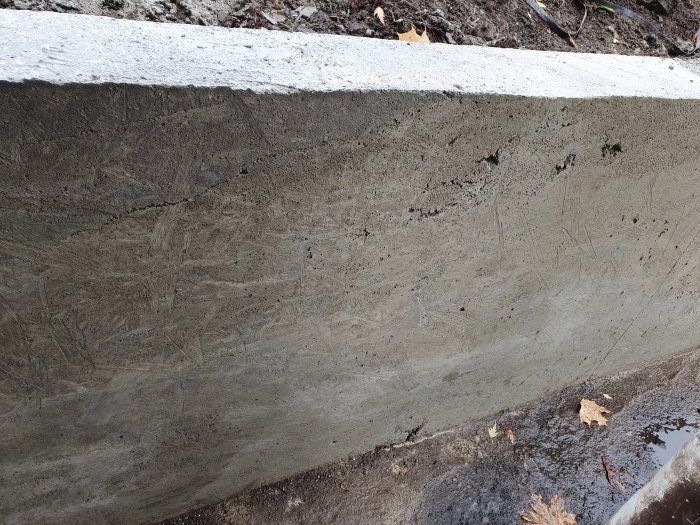 Nyligen gjuten betongstödmur med synliga håligheter och ojämnheter på ytan.