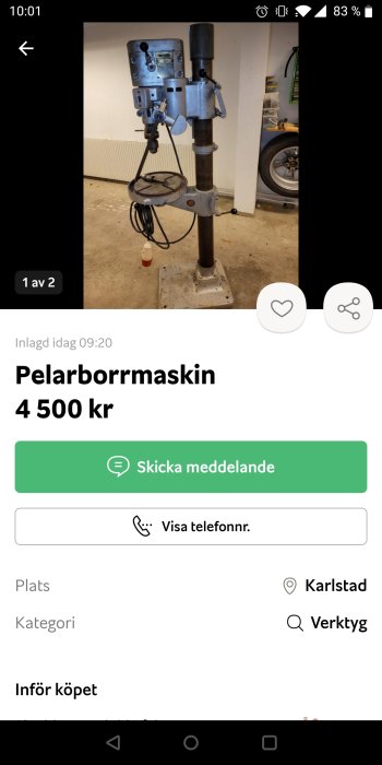 Pelarborrmaskin stående i ett garage med synliga elsladdar och stödbord.