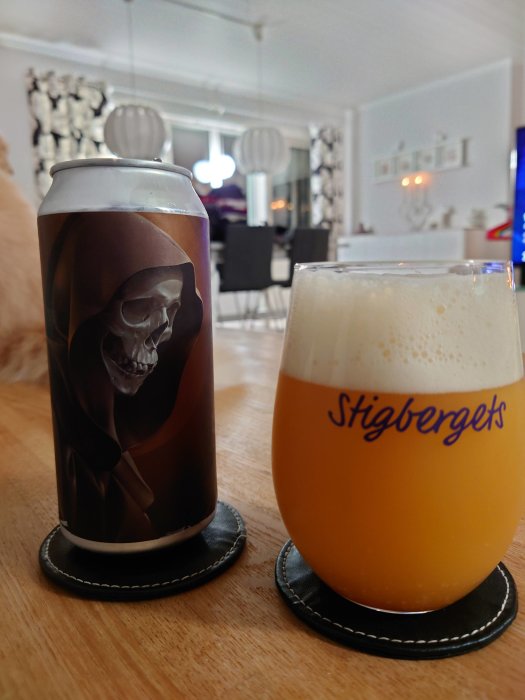 Burk från Northern Monk och ett glas med öl på bord inomhus, Stigbergets-logotyp på glaset.