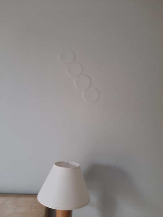 Vägg med inspacklade cirkelformade dosor ovanför en bordslampa.