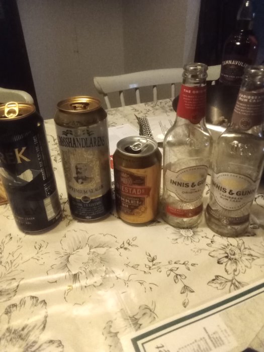 Ölburkar och tomma spritflaskor på ett bord med blommigt duk.