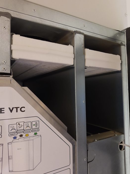 Öppnad ventilationsenhet Systemair VTC 300 med synliga filterutrymmen och instruktionsetikett.