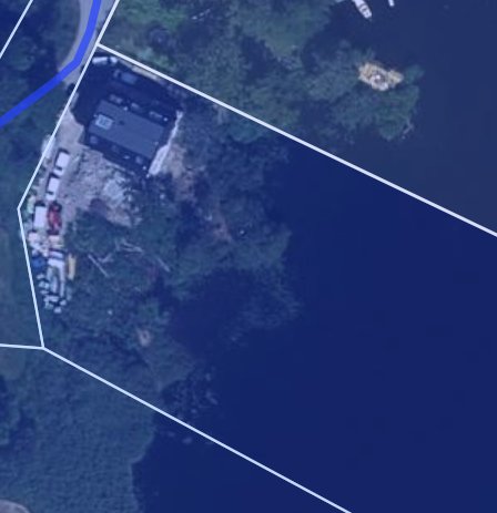 Satellitbild över sjötomten med markerade tomtgränser och husets placering i hörnet.