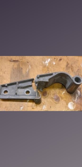 Metallbeslag i två delar på ett träbord, potentiellt till ett byggprojekt eller reparation.