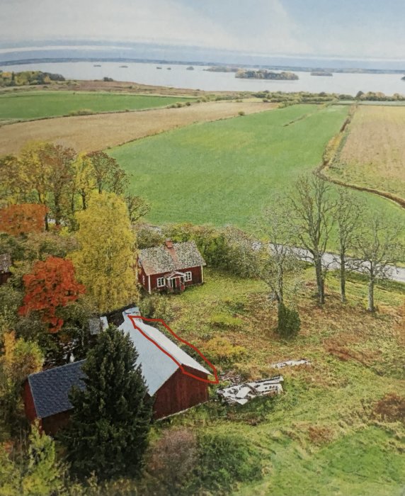 Lantgård med röda byggnader omgivna av grönt fält, en ladugård med markerat plåttak för solceller.