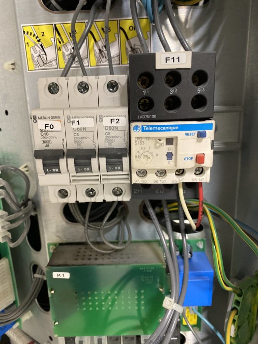 Elektriskt skåp med säkringar, småknappar och ett vred, kopplat till kablar och komponenter.