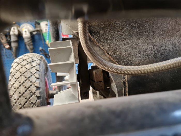Närbild av en kompressor i en verkstad med skymt av verktygstavla och del av däck.