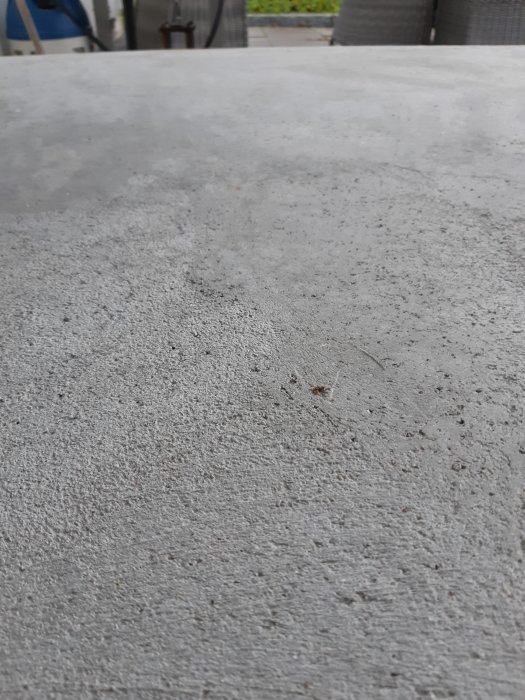 Ljusgrå, småskrovlig betongyta som är halkfri och utan mönster, simulerande en ren betongentré.