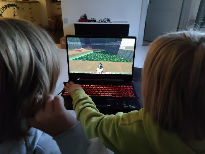 Två barn spelar ett retro videospel på en laptop.