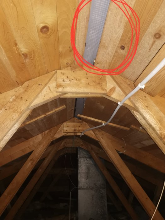 Takvind med synliga träbjälkar och en saknad planka vid nocken markerad med röd cirkel.