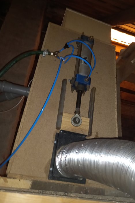 Bild på en tömningsventil och en slang ansluten till en tömningsfläkt, installerade på baksidan av en anordning.