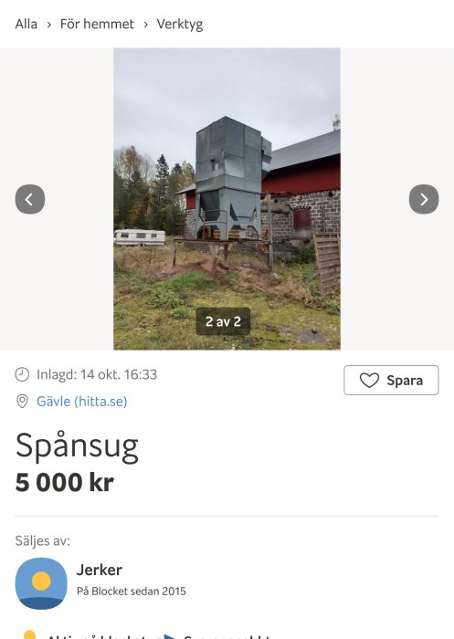 Spånsug utomhus vid röd byggnad med grå ventilationstrumma och grön natur i bakgrunden.