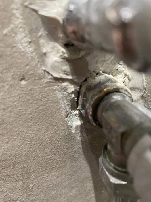 Väggrör med sprickor runt genomföringen och saknad täckbricka i ett badrum.
