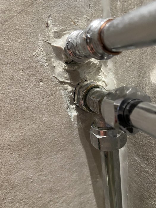 Rör som går genom en vägg med synliga sprickor runt genomföringen och utan täckbricka.