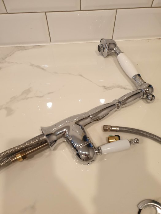 Kromad Bugnatese blandare modell 6388 med utdragbar del, guld-mutter och anslutningsslangar på marmorbänk.