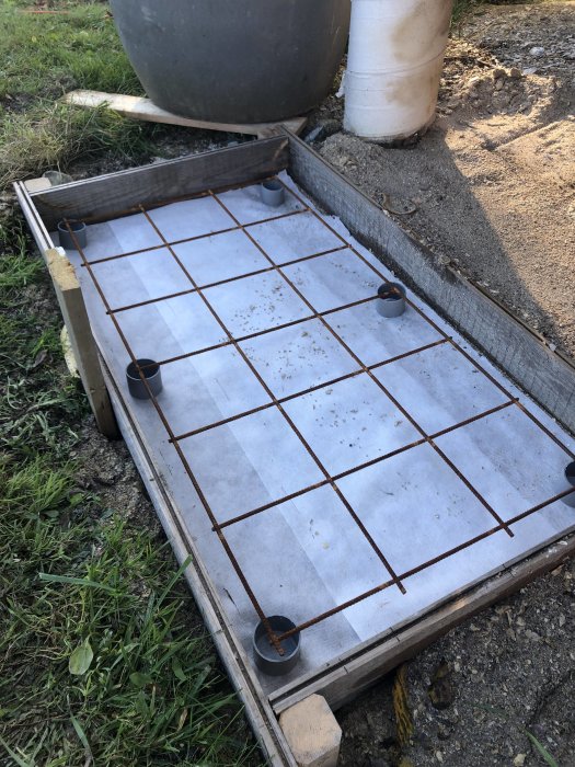 Nygguten betongplatta med armeringsjärn och isoleringsduk, förberedd för värmepumpsinstallation.