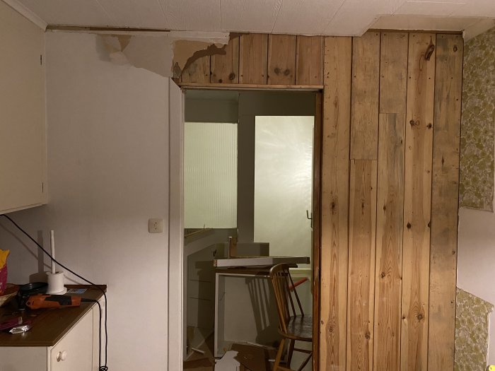 Delvis avtäckt vägg med synlig träpanel och öppning för skjutdörr i ett hem under renovering.