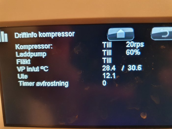 Display på värmepump som visar driftinformation inklusive kompressorns status och temperaturvärden.