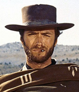 Man i cowboyhatt och poncho med grässtrå i munnen mot en bakgrund av karga kullar.