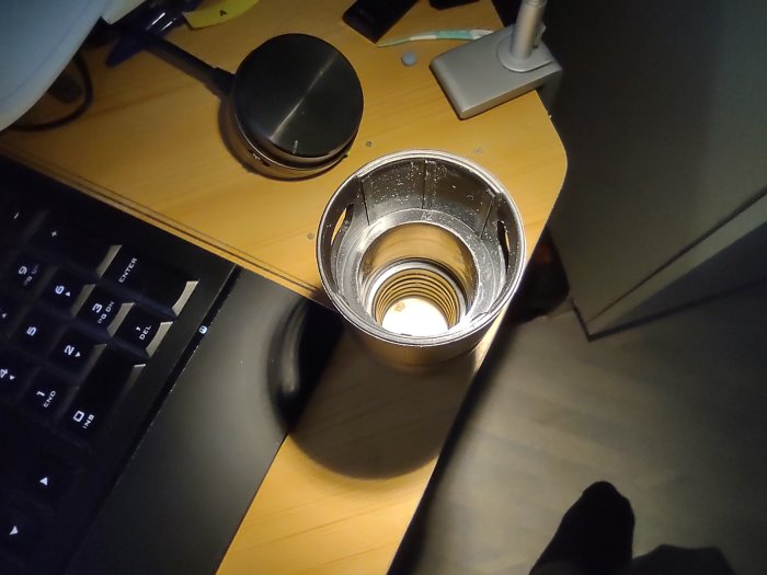 Överblick av en metalladapter med trådar på insidan, placerad på ett skrivbord nära ett tangentbord och en datormus.