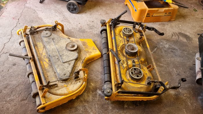 Åldrad Stiga Park åkgräsklippare från 80-talet med synlig slitage och demonterade delar på ett garagegolv.
