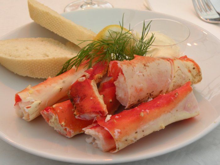 Kungskrabbsticks på tallrik med bröd, dill och sås, föreställande lyxig skaldjursmåltid.