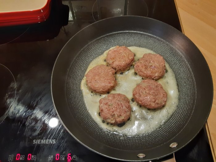 Fem hemgjorda jägarbiffar av blandfärs från vildsvin och älg steks i en panna.