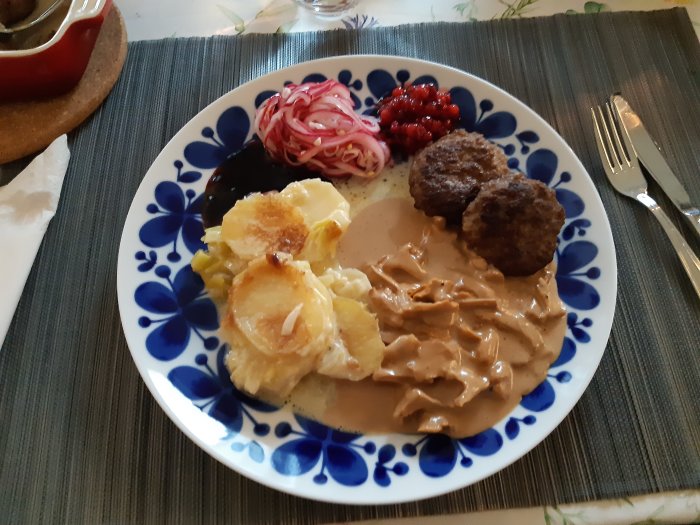 Tallrik med vildsvin och älgfärsbiffar, potatisgratäng, gräddsås med kantareller, vinbärsgele, rårörda lingon, picklad rödlök.