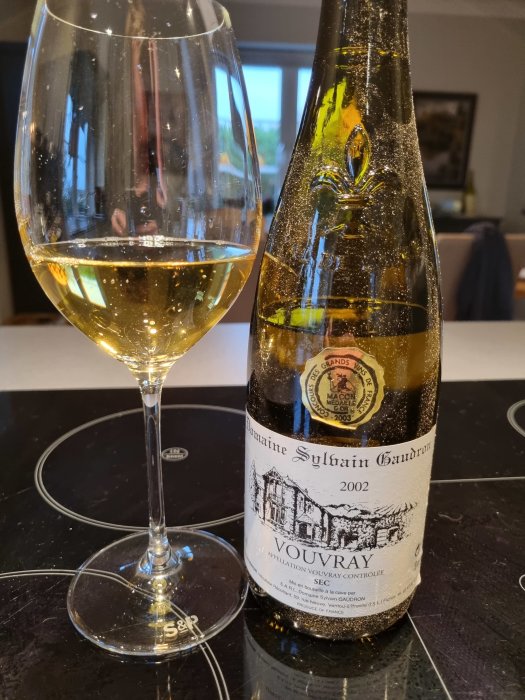 Flaska och glas med gyllene vin, etikett visar "Domaine Sylvain Gaudron Vouvray 2002".