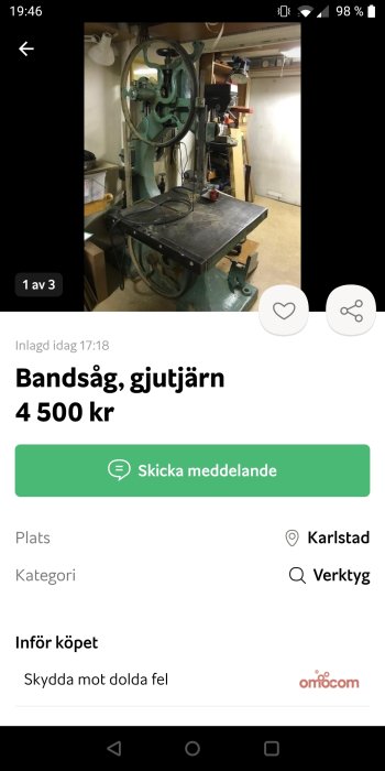 Gammal bandsåg i gjutjärn monterad på ett arbetsbord i ett verkstadsutrymme.